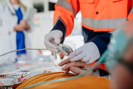 Foto de Primer plano de los rescatistas que cuidan al paciente desde la ambulancia, dándole una máquina de electrocardiograma. - Imagen libre de derechos