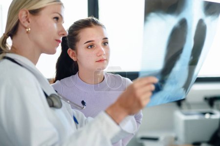 Photo for Young woman doctor showing x-ray image of lungs to the patient. - Royalty Free Image