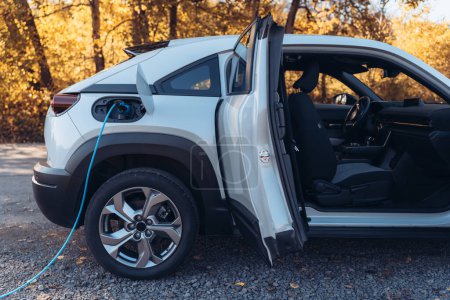 Téléchargez les photos : Chargement voiture électrique avec propre chargeur dans la maison, concept de transport durable. - en image libre de droit
