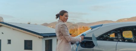 Téléchargez les photos : Jeune femme chargeur de voiture dans la maison, concept de transport durable et économique. - en image libre de droit