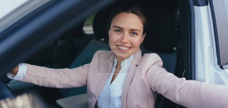 Téléchargez les photos : Jeune femme excitée assise dans sa voiture, prête à conduire. - en image libre de droit