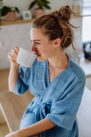 Photo for Young woman enjoying cup of coffee at morning, in a kitchen. - Royalty Free Image