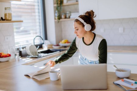 Téléchargez les photos : Jeune femme ayant son bureau à domicile dans une cuisine. - en image libre de droit