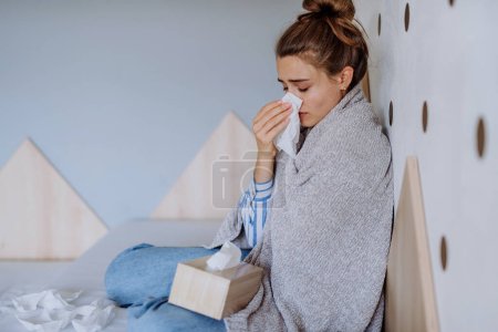 Kranke Frau sitzt erkältet im Bett.