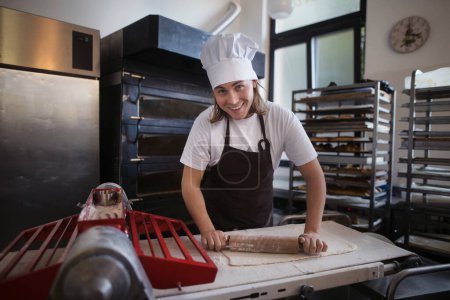 Photo for Young baker with chef cap preparing pastries in a bakery. - Royalty Free Image
