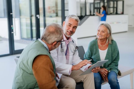 Téléchargez les photos : Médecin mature parlant avec les patients âgés dans le couloir de l'hôpital. - en image libre de droit