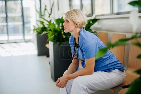 Téléchargez les photos : Jeune médecin cher assis dans un couloir d'hôpital. - en image libre de droit