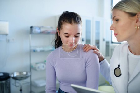 Foto de Primer plano del médico consolando a una adolescente infeliz en la oficina de la ambulancia. - Imagen libre de derechos