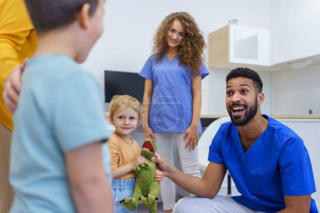 Young multiracial dentist playing with kids at his office in dentist clinic.