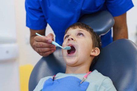 Téléchargez les photos : Portrait d'un garçon liitle lors d'un examen de dentiste. - en image libre de droit
