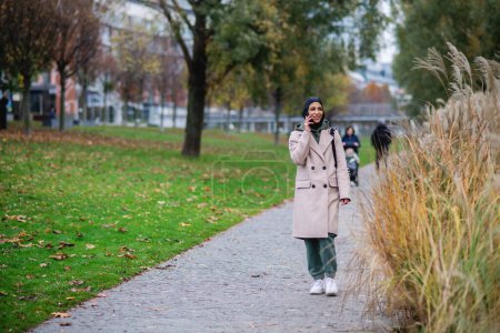 Photo for Young muslim woman walking and calling in city. - Royalty Free Image