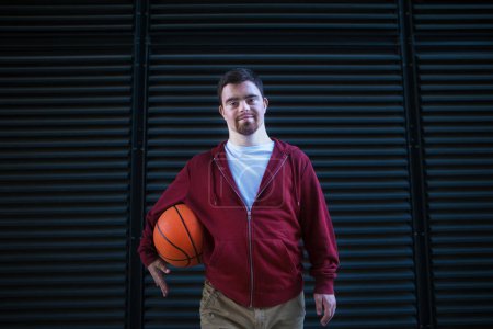 Photo for Portrait of young man with down syndrom holding a basketball ball. - Royalty Free Image