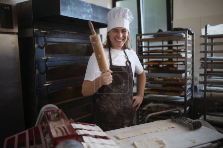 Foto de Panadero joven con tapa de chef preparando pasteles en una panadería. - Imagen libre de derechos