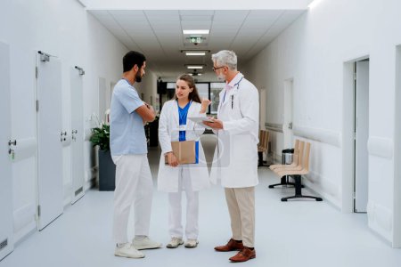 Photo for Team of doctors discussing something at a hospital corridor. - Royalty Free Image