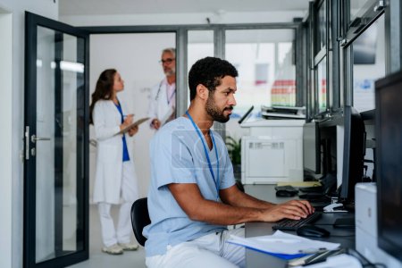 Téléchargez les photos : Jeune médecin travaillant sur ordinateur dans le bureau de l'hôpital. - en image libre de droit