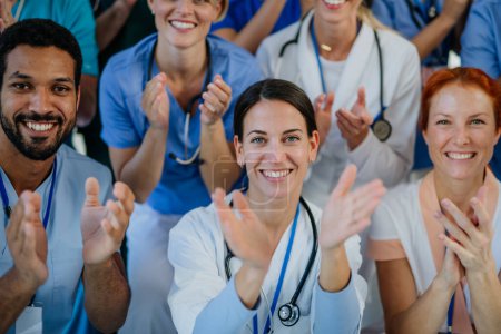 Photo for Portrait of happy doctors, nurses and other medical staff clapping, in a hospital. - Royalty Free Image