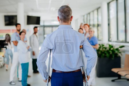 Photo for Medical staff clapping to patient who recovered from a serious accident. - Royalty Free Image