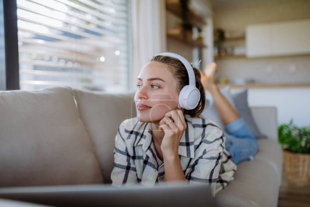 Photo for Young woman resting on sofa and listening the music. - Royalty Free Image