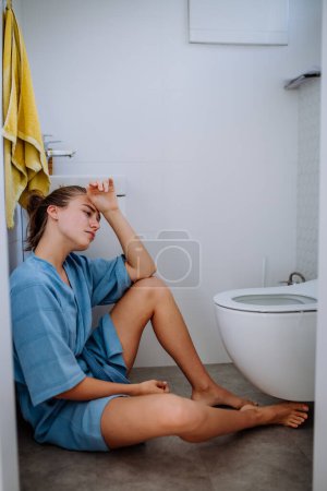 Foto de Mujer embarazada joven sentada en el suelo cerca del baño. - Imagen libre de derechos