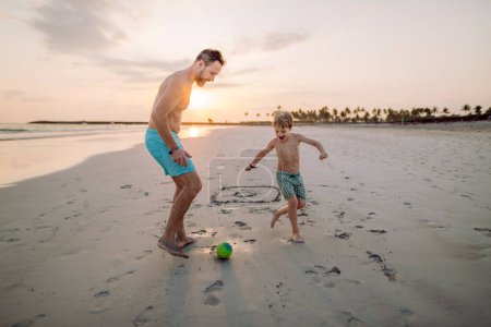 Téléchargez les photos : Père avec son fils plaçant le football sur une plage. - en image libre de droit