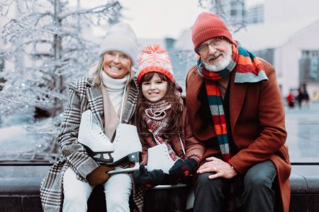 Photo for Portrait of seniors and their granddaughter in a winter at outdoor ice skating rink. - Royalty Free Image