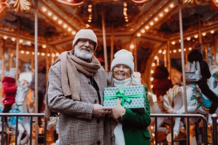 Photo for Happy senior couple enjoying outdoor christmas market, buying gifts. - Royalty Free Image
