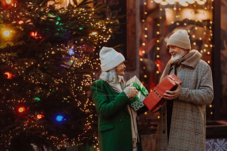 Glückliches Seniorenpaar genießt Weihnachtsmarkt im Freien, kauft Geschenke.