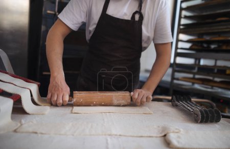 Téléchargez les photos : Gros plan d'un boulanger préparant des pâtisseries dans une boulangerie. - en image libre de droit