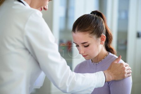 Photo for Close-up of doctor consoling unhappy teenage girl in the ambulance office. - Royalty Free Image
