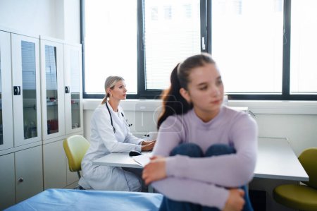 Téléchargez les photos : Adolescente malheureuse assise dans un bureau de médecins. - en image libre de droit