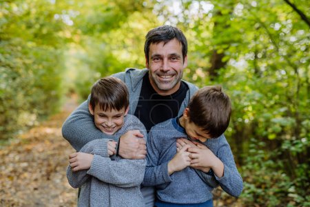 Téléchargez les photos : Father having fun with his sons in a forest. - en image libre de droit