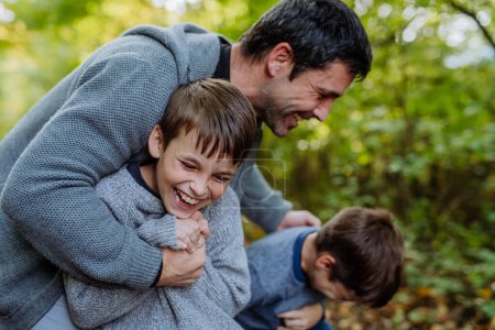 Photo for Father having fun with his sons in a forest. - Royalty Free Image