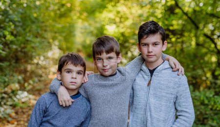 Téléchargez les photos : Portrait of three boys, brothers standing in a forest. - en image libre de droit