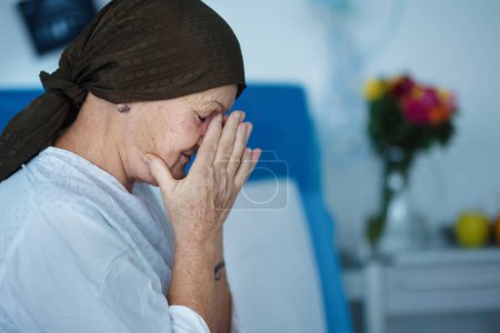 Téléchargez les photos : Femme âgée assise dans la chambre d'hôpital après la chimiothérapie. - en image libre de droit