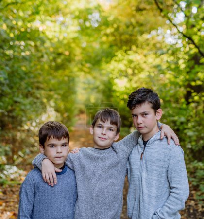 Foto de Portrait of three boys, brothers standing in a forest. - Imagen libre de derechos