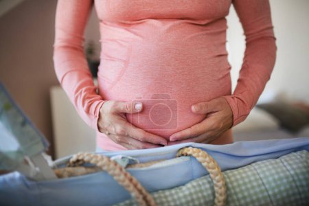 Téléchargez les photos : Close-up of a pregnant woman preparing for baby, stroking her belly. - en image libre de droit
