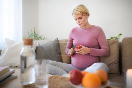 Téléchargez les photos : Vue grand angle de la femme enceinte coupant une pomme. - en image libre de droit