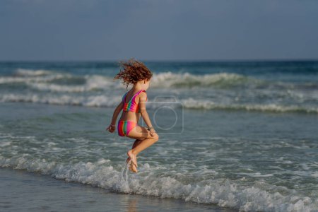 Photo for Little girl in swimsuit jumping in the sea, enjoying summer holiday. - Royalty Free Image