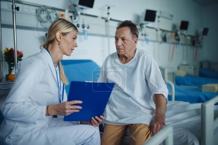 Téléchargez les photos : Jeune femme médecin expliquant le diagnostic à sa patiente dans la chambre d'hôpital. - en image libre de droit