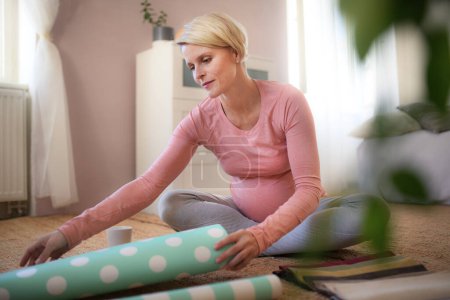 Téléchargez les photos : Happy pregnant woman choosing fabrics and wallpapers to the childs room. - en image libre de droit