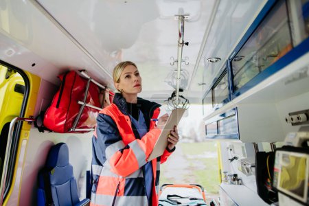 Téléchargez les photos : Young rescuer doctor checking equipment in an ambulance car. - en image libre de droit