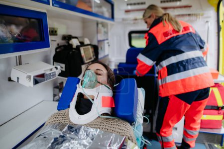Téléchargez les photos : Rescuer taking care of a patient, preparing her for transport. - en image libre de droit