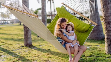 Photo for Mother with her daughter enjoying their holiday in exotic country, lying in hammock. - Royalty Free Image