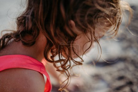 Téléchargez les photos : Close-up of little girl during playing on the beach, digging hole in the sand. - en image libre de droit