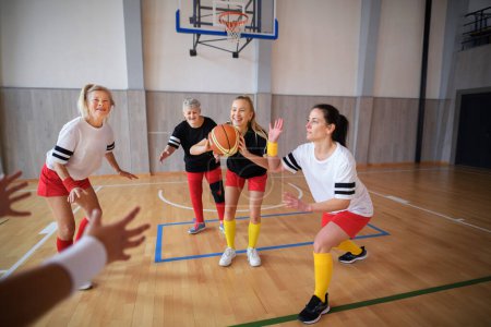 Téléchargez les photos : Femmes multigénérationnelles jouant un match de basket au gymnase. - en image libre de droit