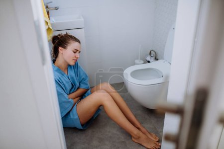 Foto de Mujer embarazada joven sentada en el suelo cerca del baño. - Imagen libre de derechos