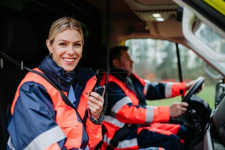 Téléchargez les photos : Portrait of a young woman doctor sitting and talking in to walkie-talkie in ambulance car. - en image libre de droit
