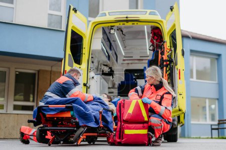 Téléchargez les photos : Rescuers taking care of a patient, preparing her for transport. - en image libre de droit