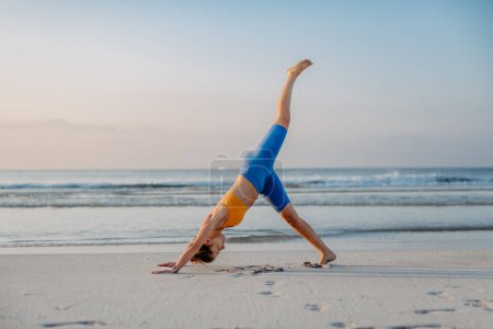 Téléchargez les photos : Jeune femme faisant des exercices à la plage, routine matinale et mode de vie sain concept. - en image libre de droit