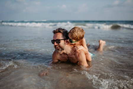 Téléchargez les photos : Father with his little son in sea, enjoying summer vacation. - en image libre de droit